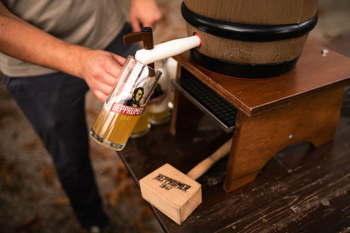 Mann, der Bier aus einem Fass zapft, unter dem Fass liegt ein Anschlaghammer mit der Aufschrift Hepprumer 1847